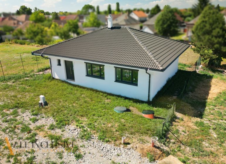 Projekt ČEREŠŇOVÁ ALEJ – 10 rod. domov/pozemk., Jelka - Rodinný dom v Jelke s úhľadnou fasádou a sedlovou strechou, obklopený záhradou.