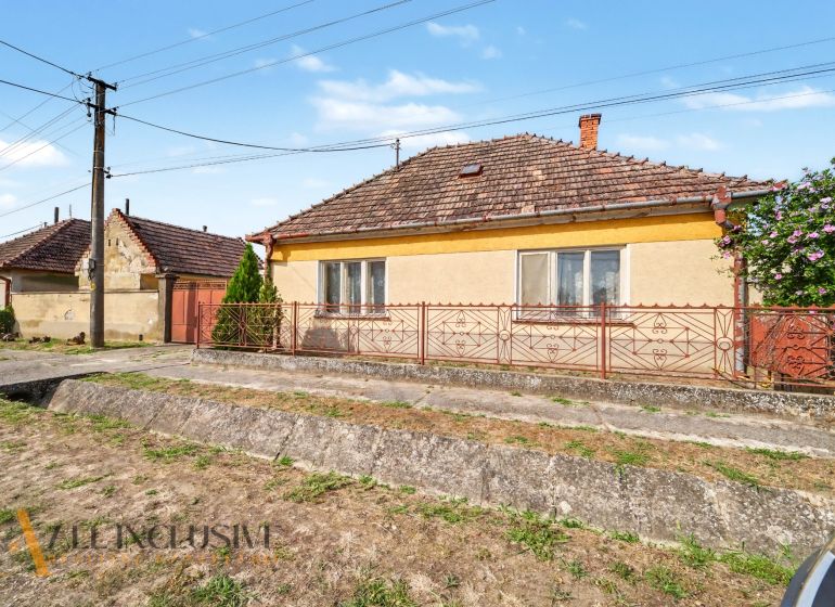Na predaj 5-izbový rodinný dom, Čierna Voda - Rodinný dom na ulici Čierna Voda v Galante, s výraznou červenou bránou a plotom.