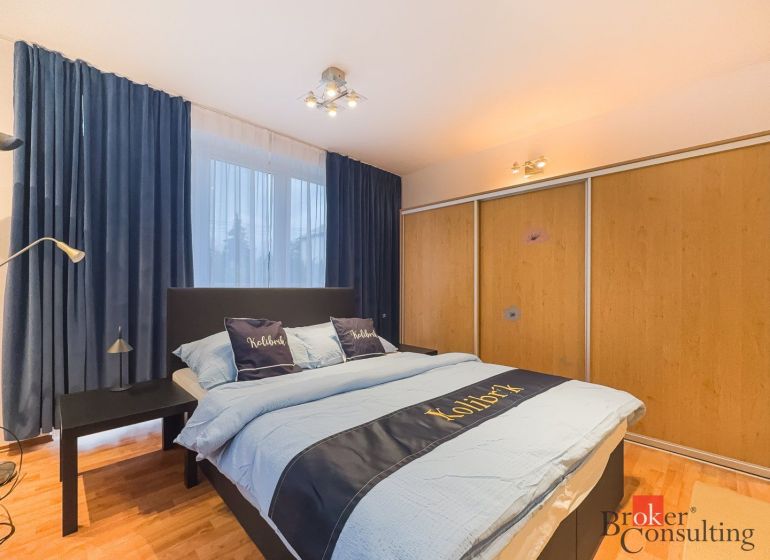 Zariadený 1i apartmán s balkónom na Hradnom kopci - Spálňa v 1-izbovom byte so závesmi, vstavanou skriňou a podlahou s dreveným dekorom.