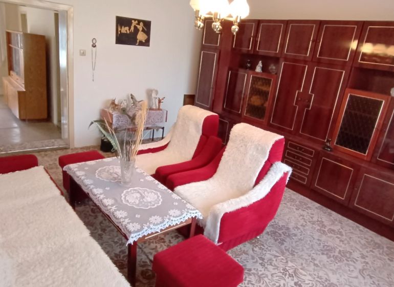 Na predaj starší rodinný dom v meste Nesvady - Obývacia izba v rodinnom dome s červenými kreslami a veľkou drevenou stenou.