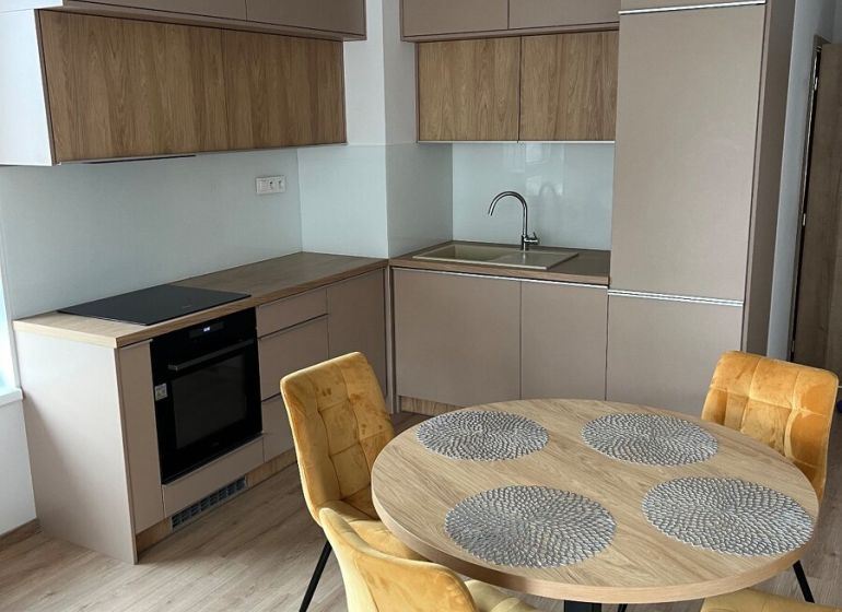 Kompletne zariadený 3-izbový byt s balkónom | PRÚDY Trnava - Kuchyňa v 3-izbovom byte s podlahou s dreveným dekorom a jedálenským stolom.