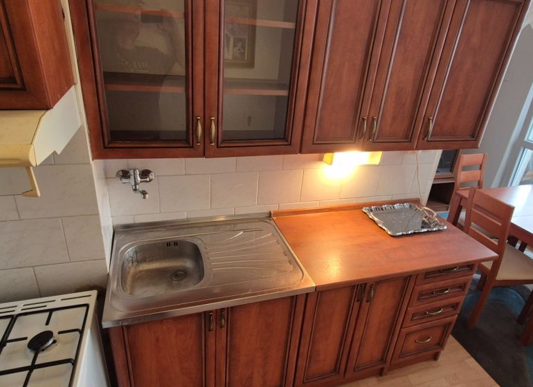 Na predaj 2 izbový byt 62m2 s 3 balkónmi - Nové Zámky  - Kuchyňa v 2-izbovom byte s drevenými kuchynskými skrinkami a jedálenským stolom.
