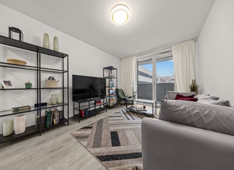 NA PREDAJ: 3-izbový apartmán, MATADORKA, Bratislava - Petržalka - Obývacia izba s podlahou s dreveným dekorom, pohovkou a policami v 3-izbovom byte.