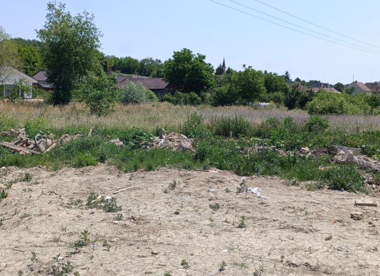 Na predaj investičný pozemok v obci Čechy - Pozemok na bývanie v Čechách so zeleňou a niekoľkými domami v pozadí.