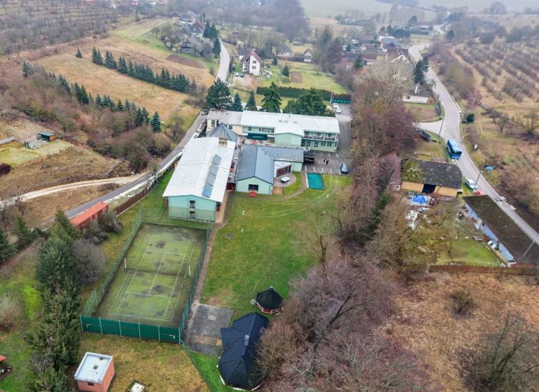 Kopanice Resort | Výnosová investícia - Letecký pohľad na Hotely a penzióny v Podkylave s tenisovým kurtom a zelenými plochami.