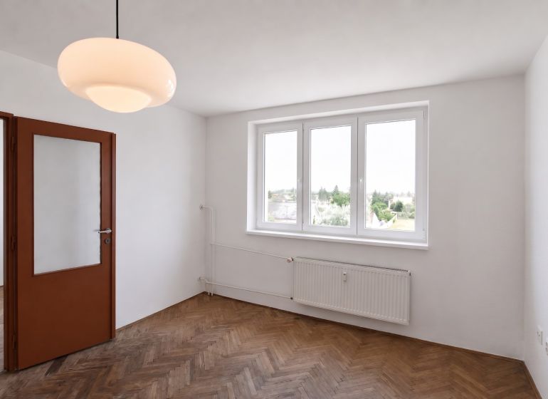 Priestranný 3-izbový byt | 72 m² + 9 m² loggia + 9 m² pivnica |  - Izba so svietidlom a podlahou s dreveným dekorom v 3-izbovom byte.