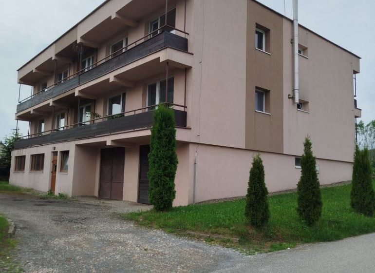 Garsónka - Trojposchodový bytový dom v Ľubotíne na ulici Na Rovni s balkónmi a zeleňou.