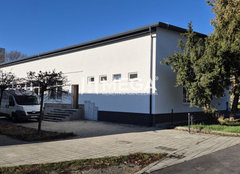PREDAJ OBCHODNÉHO PRIESTORU v HUMENNOM (sídlisko 2A) - Obchodné priestory na ulici Tyršová v Humennom s bielou fasádou a stromami v okolí.