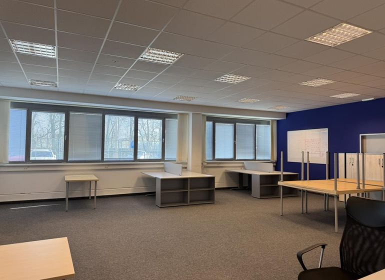Kancelárske, obchodné a skladové priestory od 14m2 do 500m2 v areáli. - Kancelársky priestor s kobercovou podlahou, veľkými oknami a kancelárskym nábytkom v skladoch a halách.