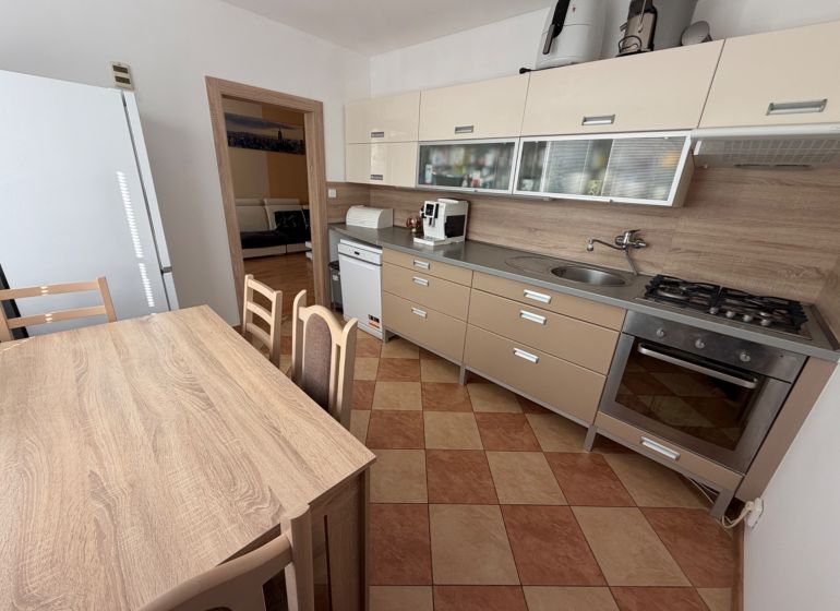 3 izbový byt s balkónom Topoľčany  - Kuchyňa 3-izbového bytu s rohovou linkou, jedálenským stolom a spotrebičmi.