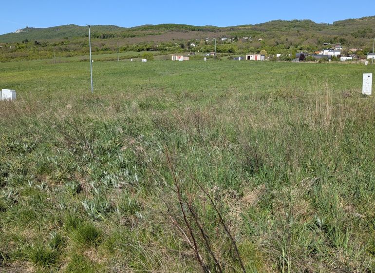 Stavebný pozemok v Štitároch 764 m2 s výhľadom na Nitru - Pozemky - bývanie v Štitároch obklopené zeleňou a horami na horizonte.