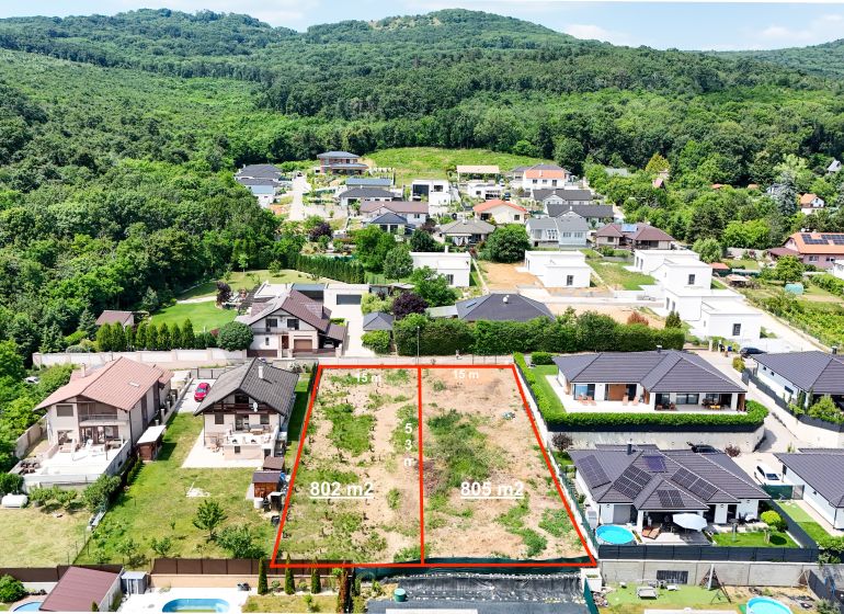 Pozemok pri lese so stavebným povolením - 805 m2 - Štitáre  - Pozemky - bývanie na ulici Pod Agátmi v Štitároch, obklopené zeleňou a domami.