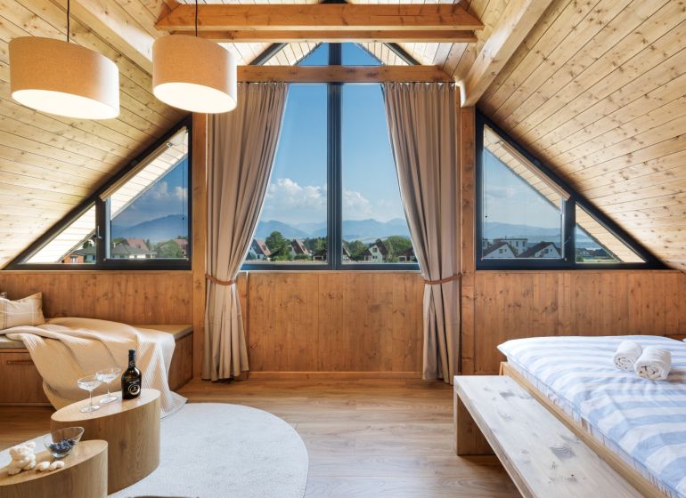 I Luxusné dvojpodlažné chalet pri Liptovskej Mare - Podkrovná izba v chate s panoramatickým výhľadom a podlahou s dreveným dekorom.