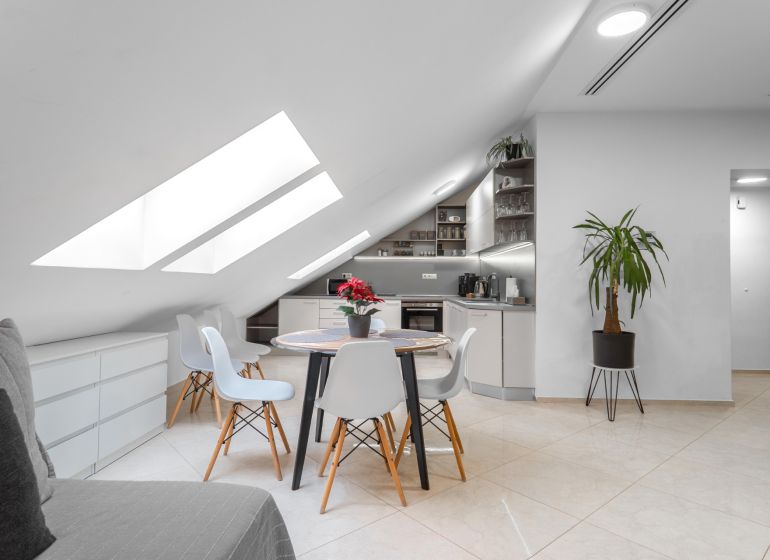 I Exkluzívny penthouse s terasou v absolútnom centre mesta - Podkrovná kuchyňa v 2-izbovom byte s okrúhlym stolom a veľkými strešnými oknami.