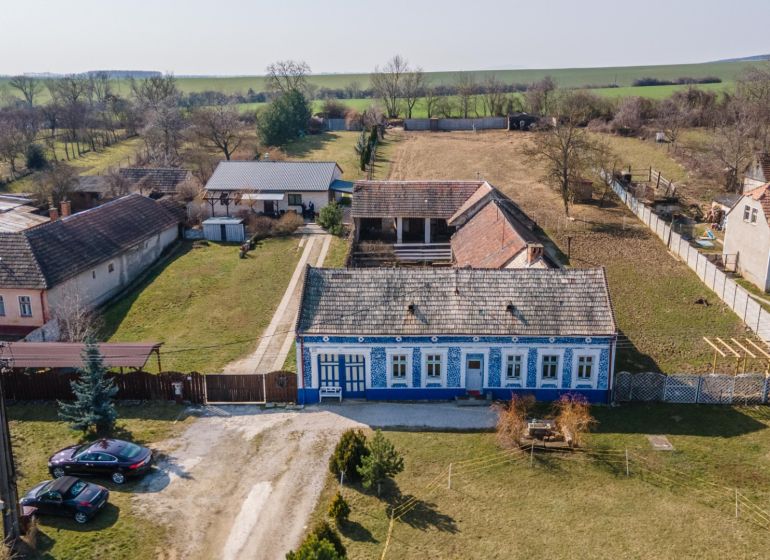 Stavebný pozemok 8 500 m² s podnikateľským potenciálom - Tradičný modrý dom s veľkým dvorom v Dolnom Lopašove, ideálny na bývanie.