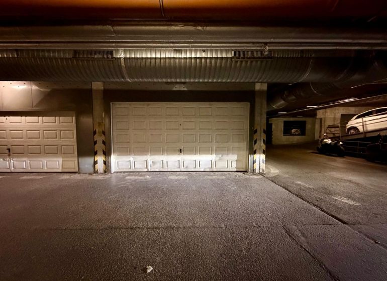 1.BCR | DVOJGARÁŽ, ELEKTRINA, KAMEROVÝ SYSTÉM, TOMÁŠIKOVA ULICA - Interiér garáží s uzavretými bránami a parkovanými vozidlami.