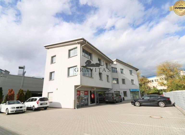 Samostatná kancelária 19,16 m2 - Lamačská cesta - Budova na ulici Lamačská cesta so zaparkovanými autami, kancelárie na prízemí, oblačné nebo.