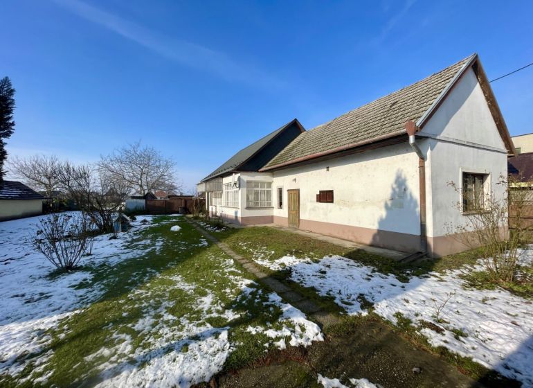 REZERVOVANÝ-VRAKÚŇ – STARÝ RODINNÝ DOM NA PREDAJ S VEĽKÝM POZEMKOM - 2 - Rodinný dom vo Vrakúni obklopený záhradou s trávnikom a zvyškami snehu.