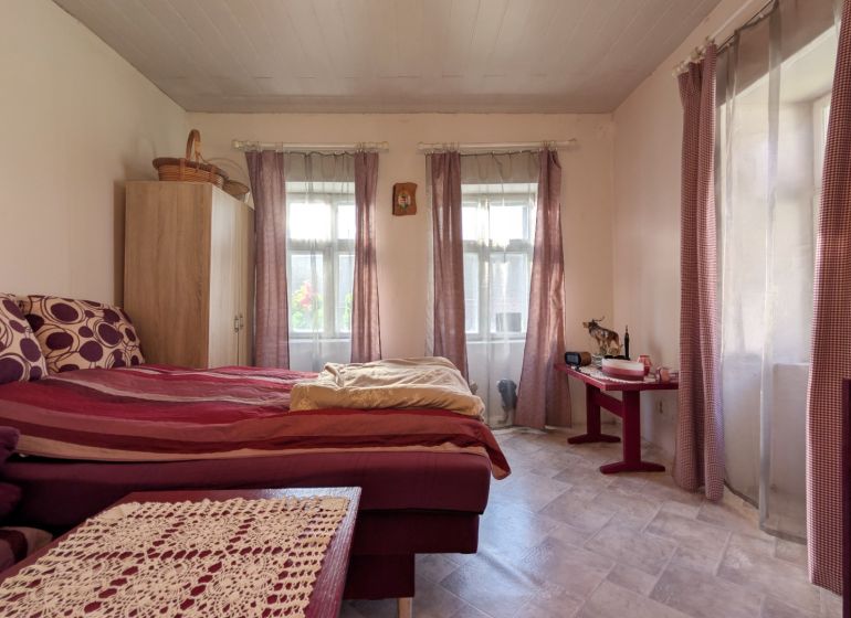 TRADIČNÝ DOM V SRDCI TAJOVA, 893 M2, TAJOV - Spálňa v rodinnom dome s posteľou, komodou a veľkými oknami s fialovými závesmi.