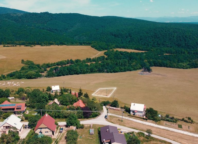 POZEMOK NA VÝSTAVBU PODHRADIE - Vidiecky pohľad na pozemky na bývanie v Podhradí obklopené lesmi a lúkami.