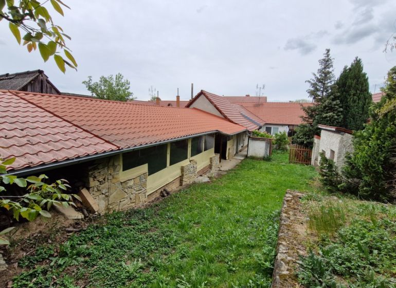 Mokrý Háj - predaj dom - Záhrada pri rodinnom dome v Mokrém Háji s kamenným múrom a červenou strešnou krytinou.