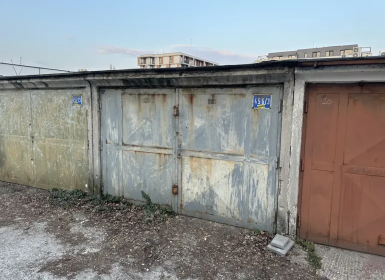 18 m2 Garáž na Sliačskej ulici v Bratislave - Opustené garáže v Bratislave - Novom Meste s opadanou omietkou a plechovými dverami.