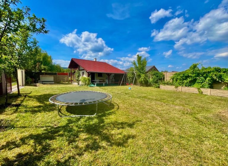 Záhrada s komfortne vybudovaným zázemím – Žabí majer - Záhrady v Bratislave – Rači na Žabom majeri s trampolínou a altánkom pod modrou oblohou.