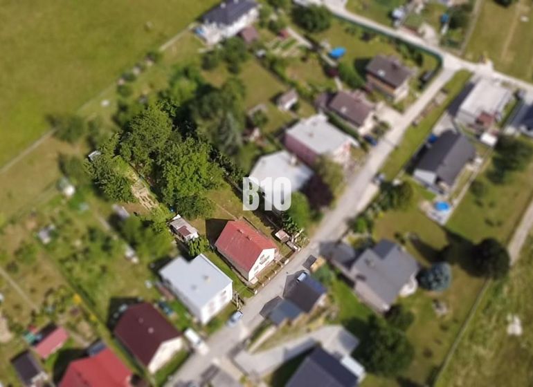 Rodinný dom s veľkým pozemkom a nádhernými výhľadmi – Dolný Milochov - Letecký pohľad na rodinný dom v Považskej Bystrici obklopený zeleňou a ďalšími domami.