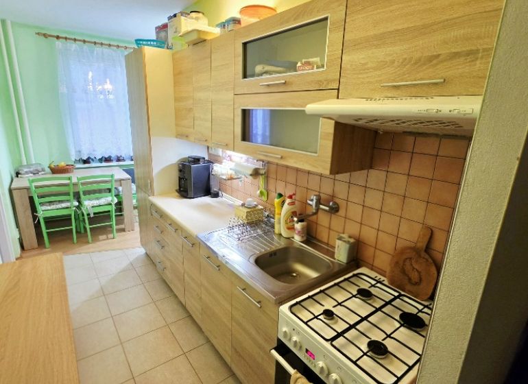 4 izbový byt Bánovce nad Bebravou /CENTRUM - STRED / 80 m2/ PIVNICA - Kuchyňa v 4-izbovom byte s dreveným dekorom a jedálenským kútom.