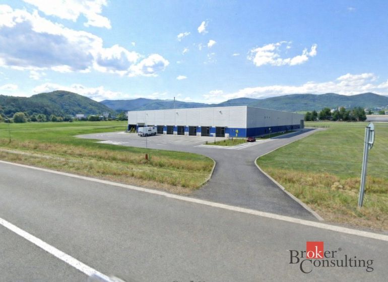Investičná príležitosť: Komerčný pozemok 8 861 m² s platnou ÚPI v Hlin - Komerčné pozemky v Hliníku nad Hronom s priemyselnou halou, obklopené kopcovitou krajinou.
