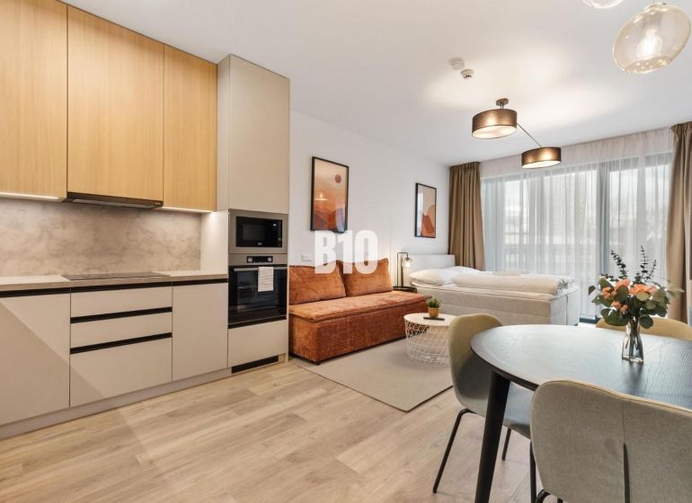 DOWNTOWN NA DOSAH – DIZAJNOVÝ 1-izbový apartmán s loggiou a výhľadom n - Kuchyňa a obývacia časť 1-izbového bytu s podlahou s dreveným dekorom.