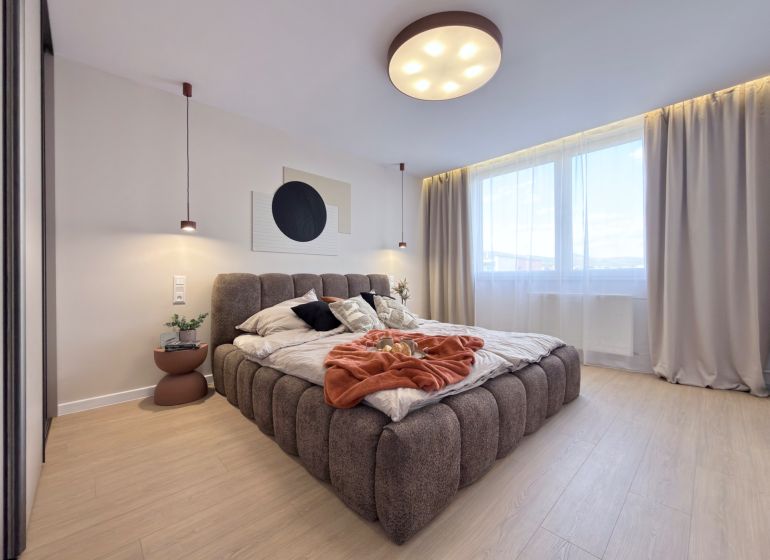 Moderný 3 izbový byt s balkónom a výhľadom na Zobor - Chrenová - Svetlá spálňa s veľkou posteľou a podlahou s dreveným dekorom v 3-izbovom byte.