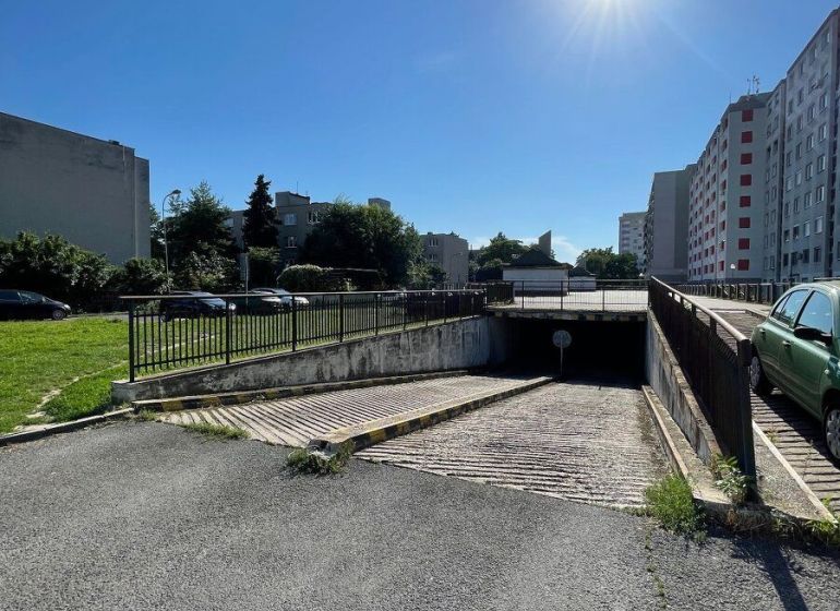 PREDAJ - Garáž na Mierovej ulici - Garáže na Mierovej ulici v Bratislave - Ružinove, obklopené panelákmi, pod modrou oblohou.