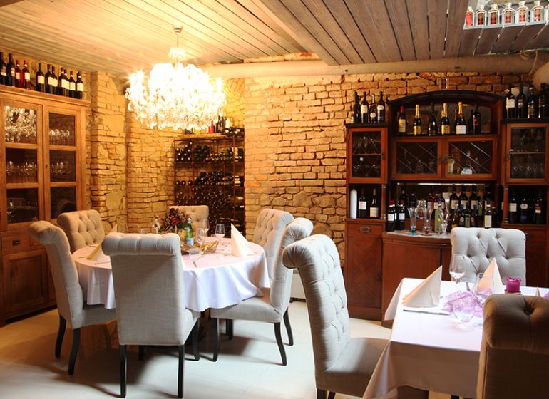 ZNÍŽENÁ CENA! I Predaj komerčného priestoru na ul. Obchodna - Reštauračné obchodné priestory s kamennými stenami a lustrom, elegantne prestreté stoly.