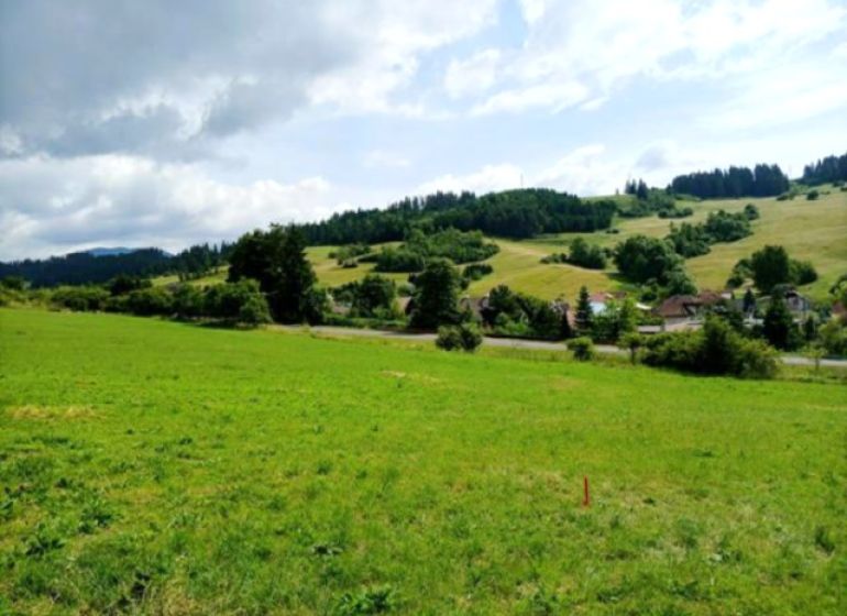 Investičný pozemok v Bešeňovej - Pozemky - komerčné v Bešeňovej, s rozľahlým trávnatým priestorom a okolitým kopcovitým prostredím.