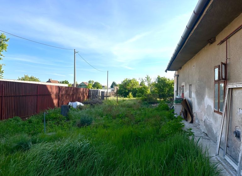Na predaj investičný pozemok s domom - Exteriér rodinného domu v meste Reca, neudržiavaná záhrada pri budove.