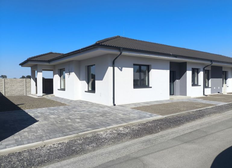 Moderný 4-izbový rodinný dom (dvojdom) v obci Vrakúň - Rodinný dom vo Vrakúni s bielou fasádou, vydláždeným chodníkom a betónovým plotom.