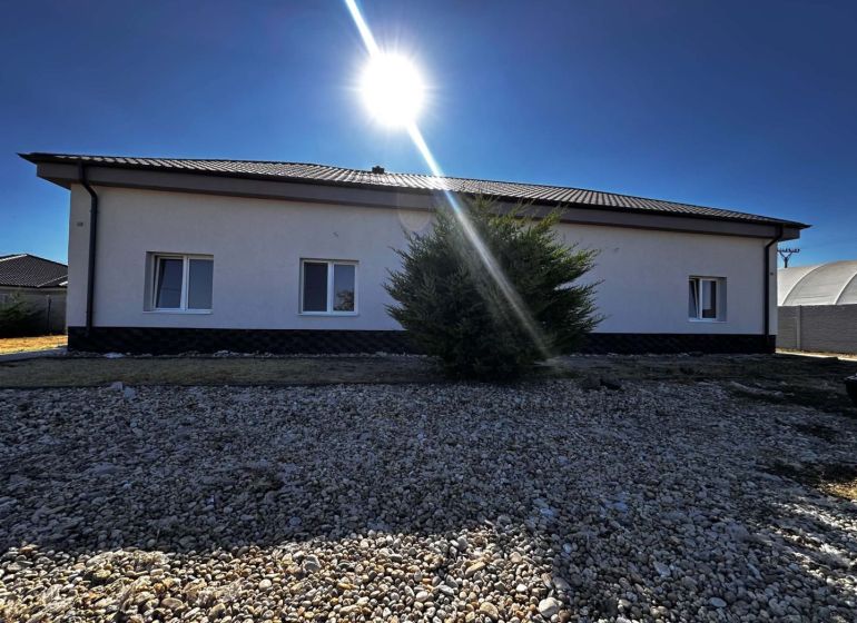 Na predaj 2-izb. byt v dvojdome (110 m²) v štandarde s krbom – Možnosť - Rodinný dom v Zemianskej Olči so slnkom na oblohe a kamenistým dvorom.