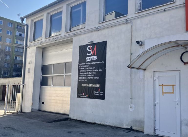 Prenájom skladový priestor v centre mesta + vlastné parkovanie - Budova v skladovom areáli v Dunajskej Strede s reklamou na detailing.
