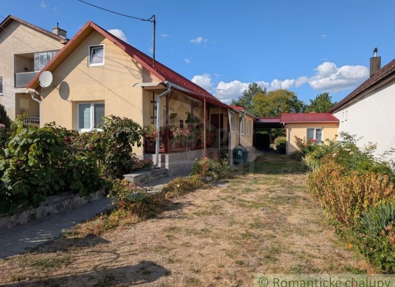 Útulný zrekonštruovaný dom / chalupa pod Slanskými vrchmi- Cabov - Rodinný dom v Cabove s červenou strechou, predzáhradkou a dláždeným chodníkom.