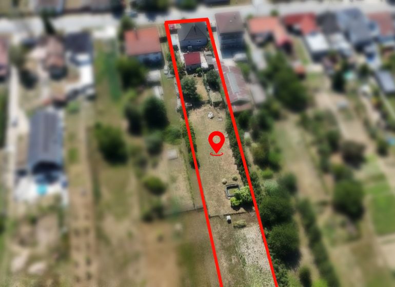 24 árov možností! Rodinný dom s veľkou záhradou v Budmericiach - Záber ulice J. Holčeka v Budmericiach s jednopodlažným rodinným domom na podlhovastom pozemku.