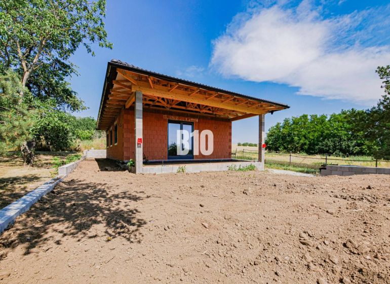 Moderný bungalov v pokojnej časti Čeľadíc – Ideálny domov na skok od N - Rodinný dom v Čeľadiciach s nedokončenou záhradou, obklopený zeleňou a modrou oblohou.