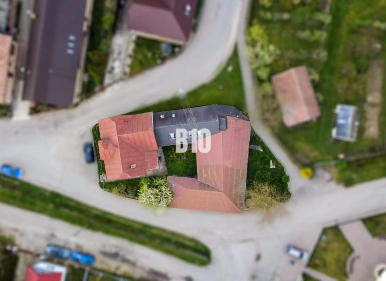 Investičná príležitosť - Dom s bývalou prevádzkou - Letecký pohľad na rodinný dom v Púchove obklopený cestami a zelenými plochami.