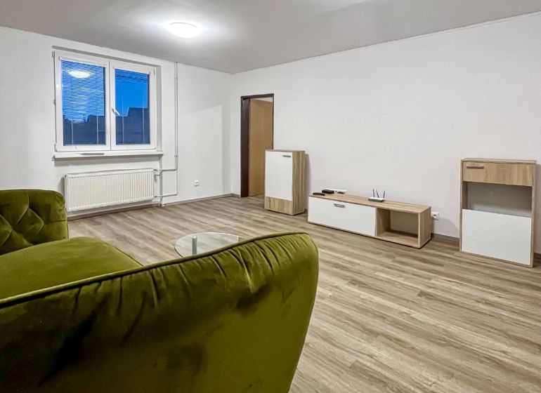 2-izbový byt 80m2 | Bratislavská - Svätý Jur - Obývačka v 2-izbovom byte s podlahou s dreveným dekorom, zelenou pohovkou a moderným nábytkom.