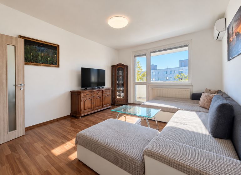 Rodinný alebo investičný 4-izbový byt, 89 m² - Obývacia izba v 4-izbovom byte s nábytkom, podlahou s dreveným dekorom a TV.