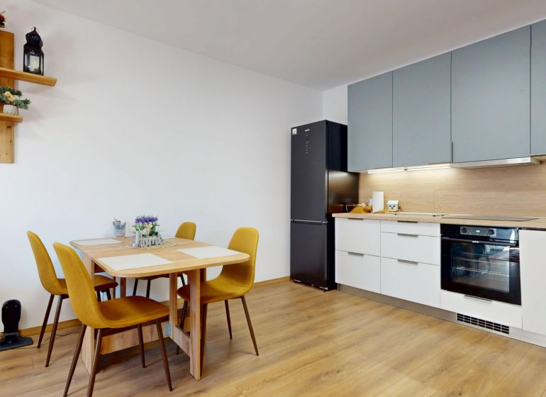 PRENÁJOM 2 izbový, zariadený byt v Danube residencia - REZERVOVANÉ - Kuchyňa v 2-izbovom byte s podlahou s dreveným dekorom, jedálenským stolom a spotrebičmi.