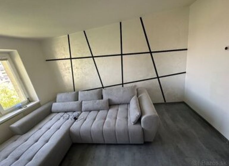 Ponúkame moderne zariadený byt na Zelenečskej  - Interiér 2-izbového bytu s pohodlnou sedačkou a podlahou s dreveným dekorom.