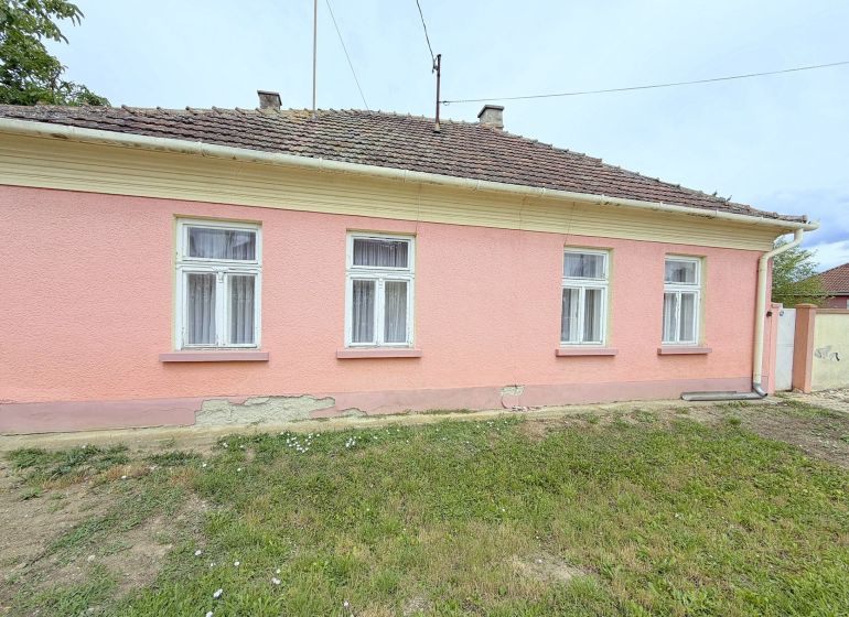 Predaj 3i rodinný dom, 900 m2 pozemok, Dunakiliti - Rodinný dom v Dunakiliti s ružovou fasádou a štyrmi oknami na prízemí.