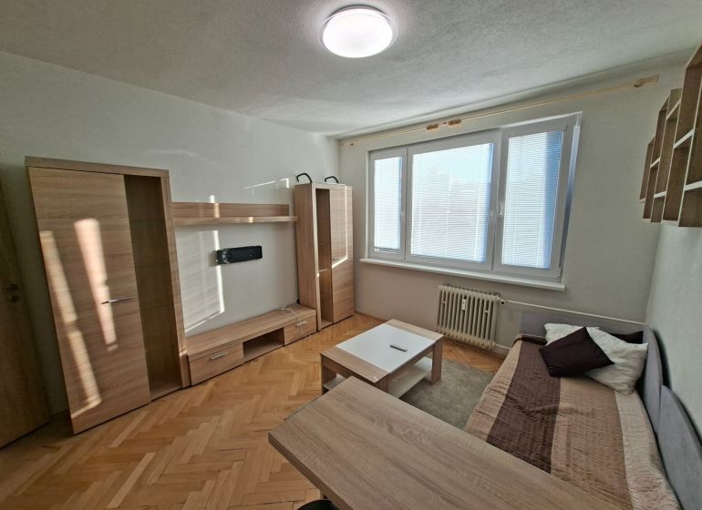 DOBRÉ REALITY-pekná garsónka na prenájom, sídl. Kopanice, Prievidza - Garsónka so svetlým nábytkom, pohovkou a podlahou s dreveným dekorom.