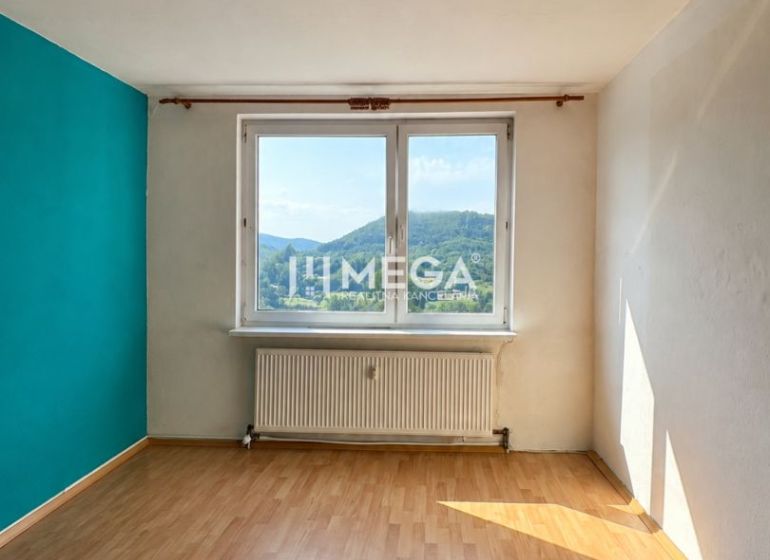 Na predaj 3 izbový byt s balkónom na Sidl.III v Humennom - Izba v 3-izbovom byte s podlahou s dreveným dekorom a výhľadom na krajinu.